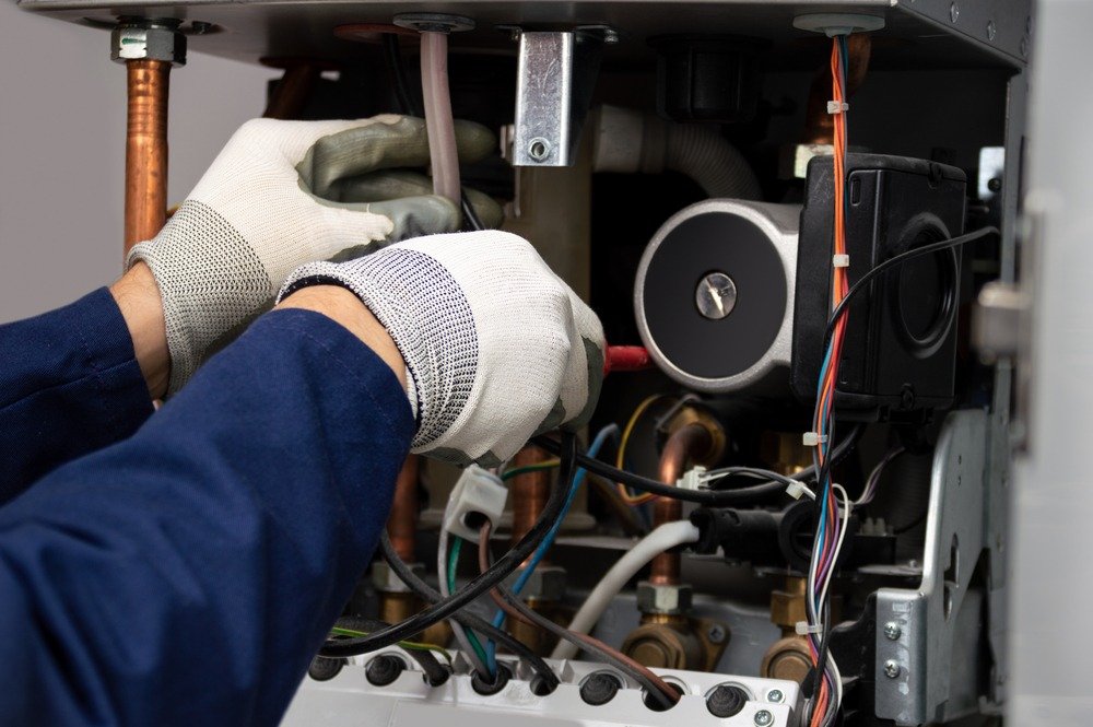 a person wearing gloves and gloves is working on a gas boiler